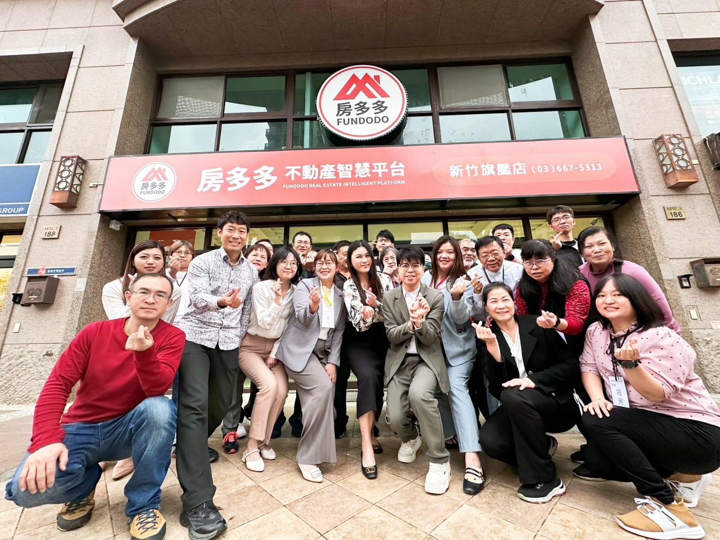 房多多不動產智慧平台新竹旗艦店前，團隊成員擺出手指愛心合影，展現投資房子的活力與熱情