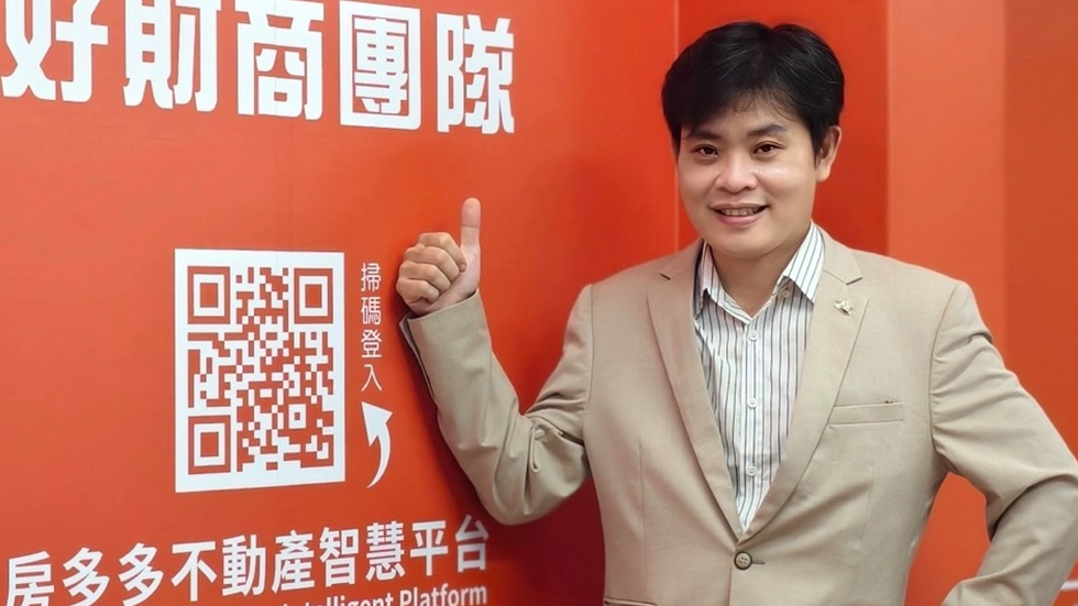 這張照片呈現一位穿著米色西裝的男士在橘色背景前豎起大拇指，旁邊有掃碼登入 QR 碼和房多多不動產智慧平台的文字，展現專業的房地產投資形象