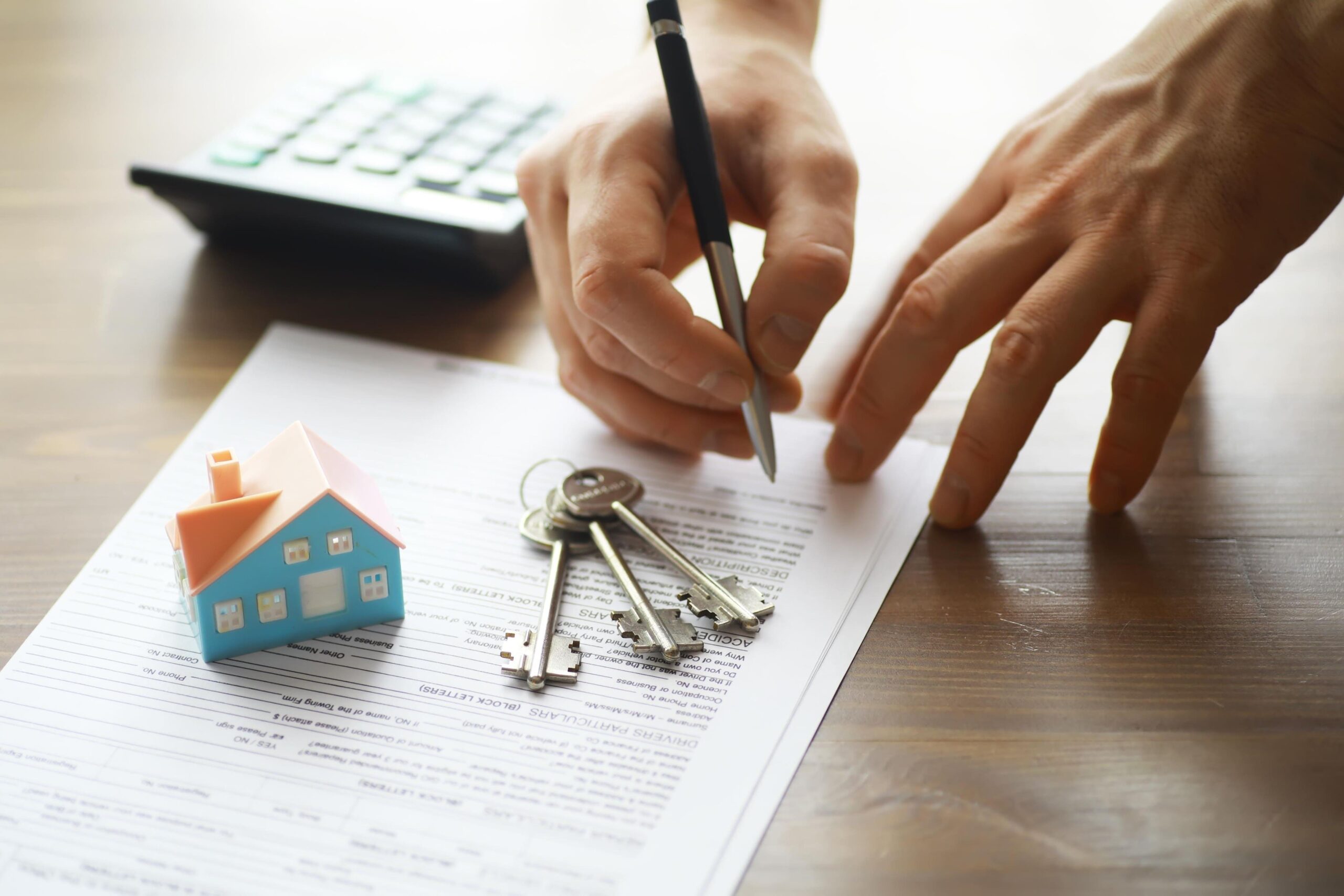手持筆在合約文件上簽名，旁邊是銳匙和小房子模型的場景，譜表買中古屋注意事項及買房流程